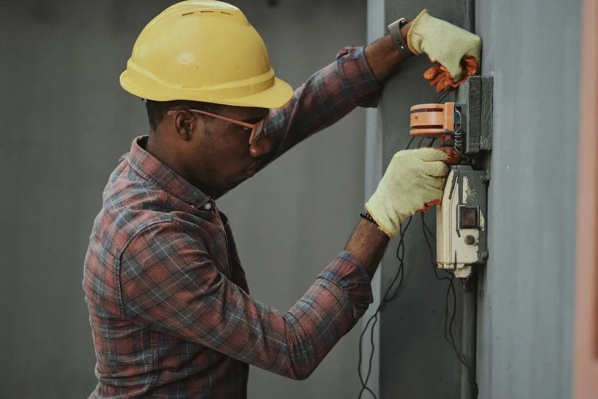Electrician in a hard hat servicing an electrical box on site